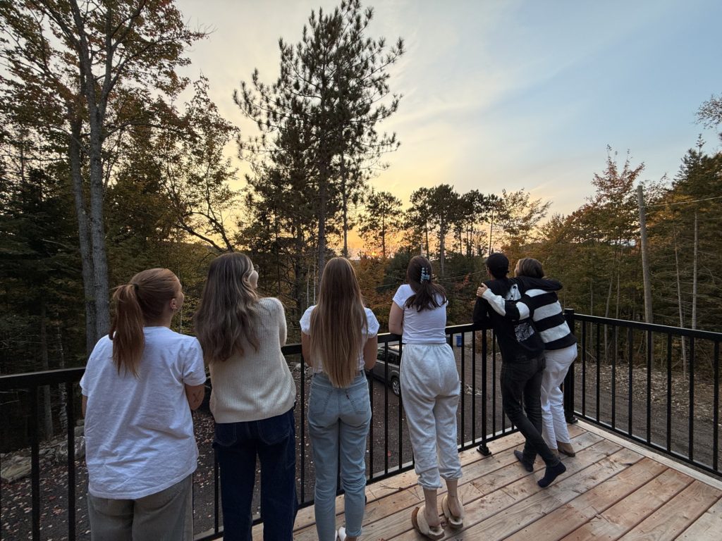 Membres de l'équipe debout sur un balcon en train de regarder un coucher de soleil