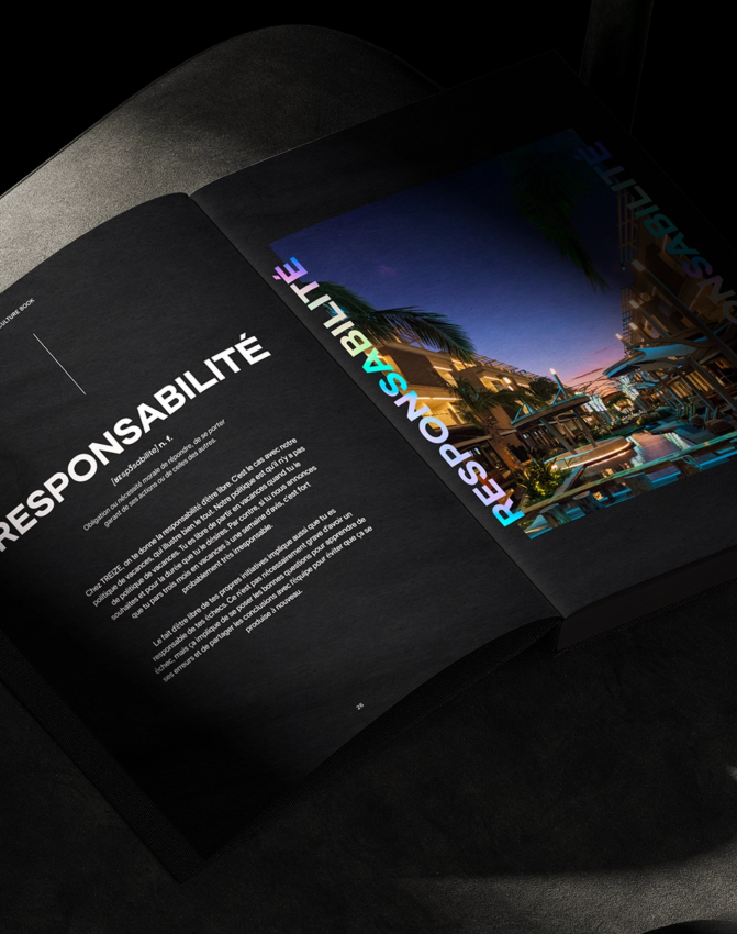 An open book on a dark chair displays a two-page spread; the left page features the word RESPONSABILITÉ in bold white letters with text below, while the right page shows a vibrant cityscape and the same word in colorful letters.